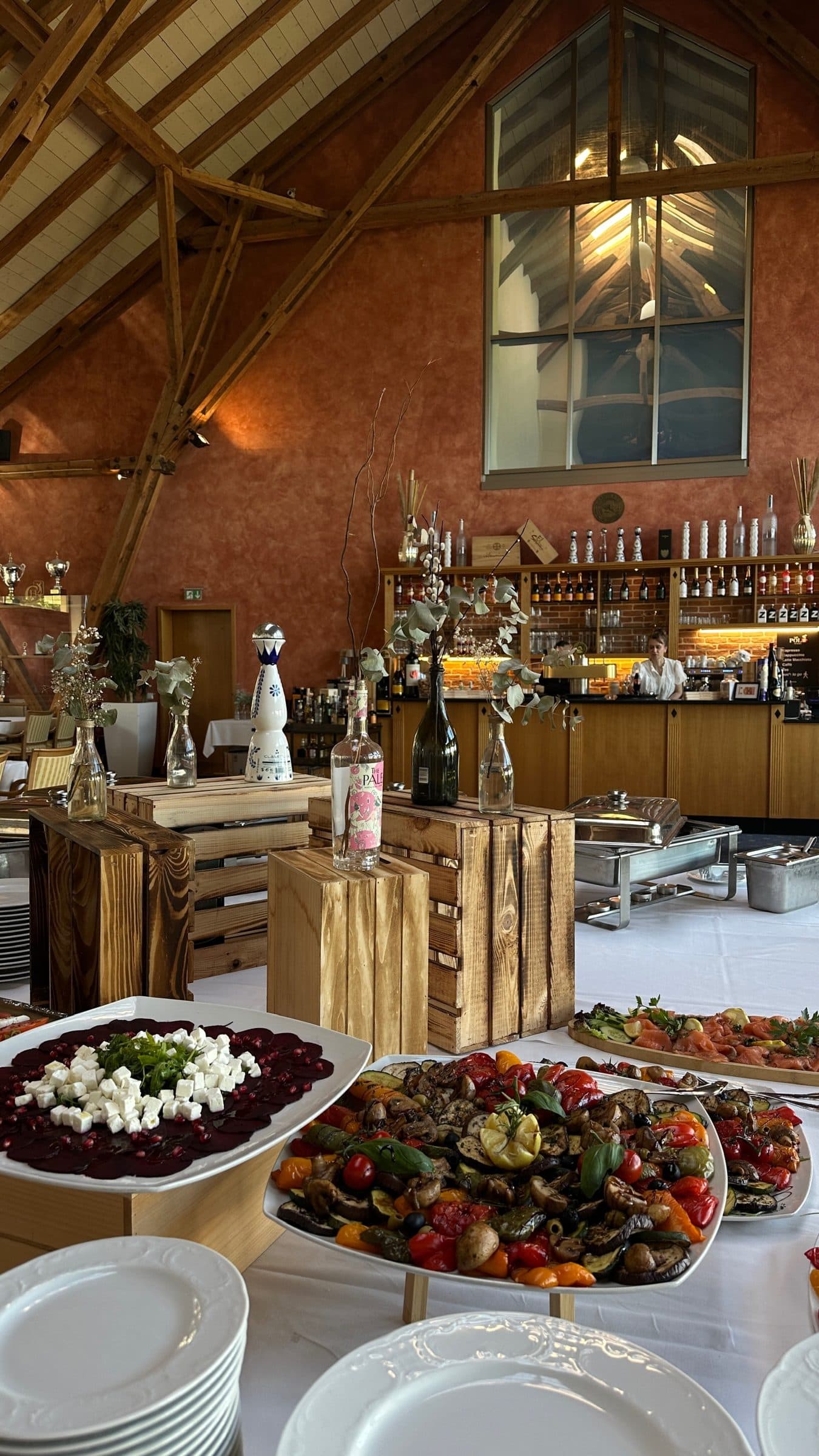 A buffet with beetroot, grilled vegetables and wooden crates, the bar beneath the gable window behind