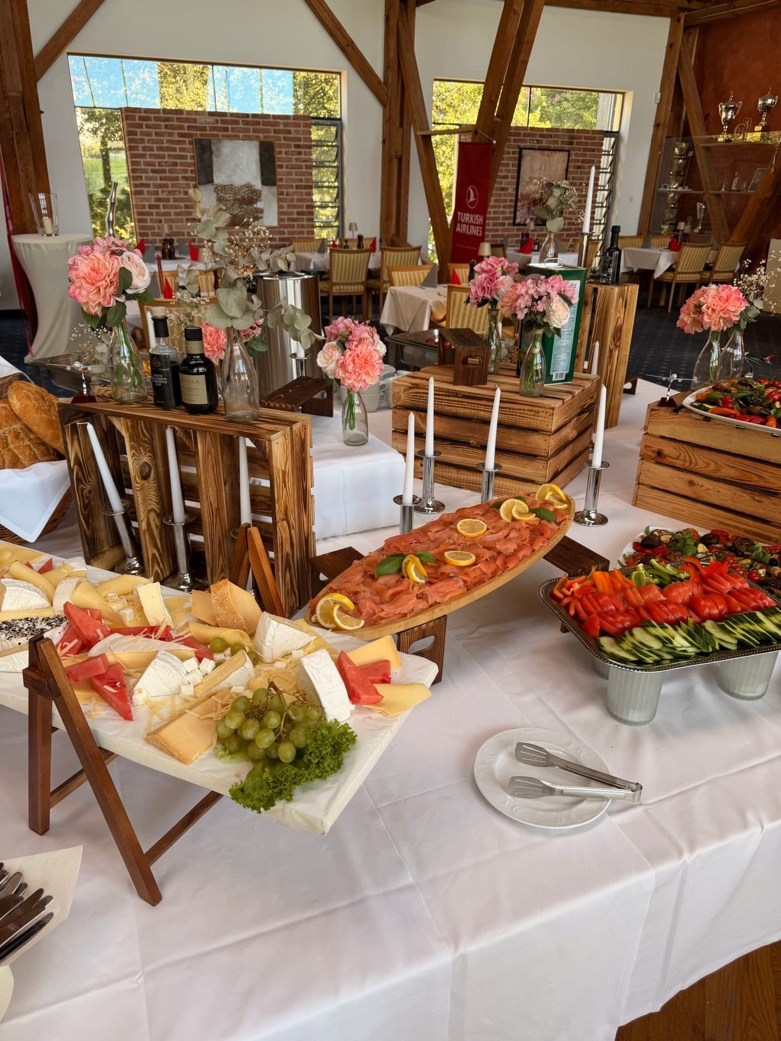 A buffet of antipasti, cheese and cured meats on wooden crates beneath the timber roof