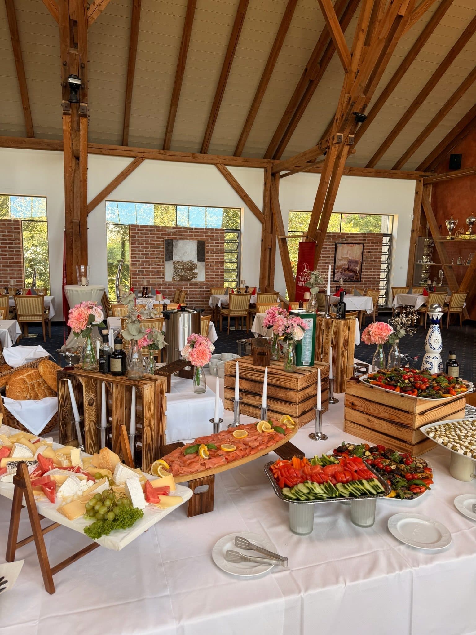 Festlich aufgebautes Buffet im Gastraum mit Blumen und Holzkisten