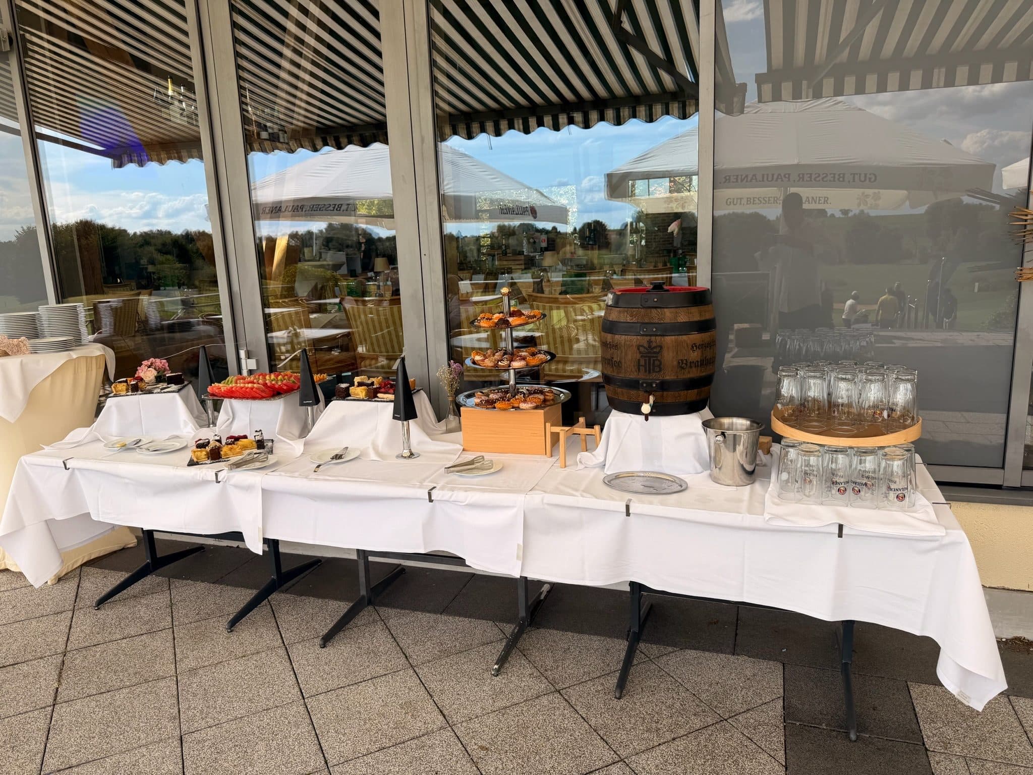 Langes Buffet auf der Terrasse unter der Markise, dahinter der Golfplatz