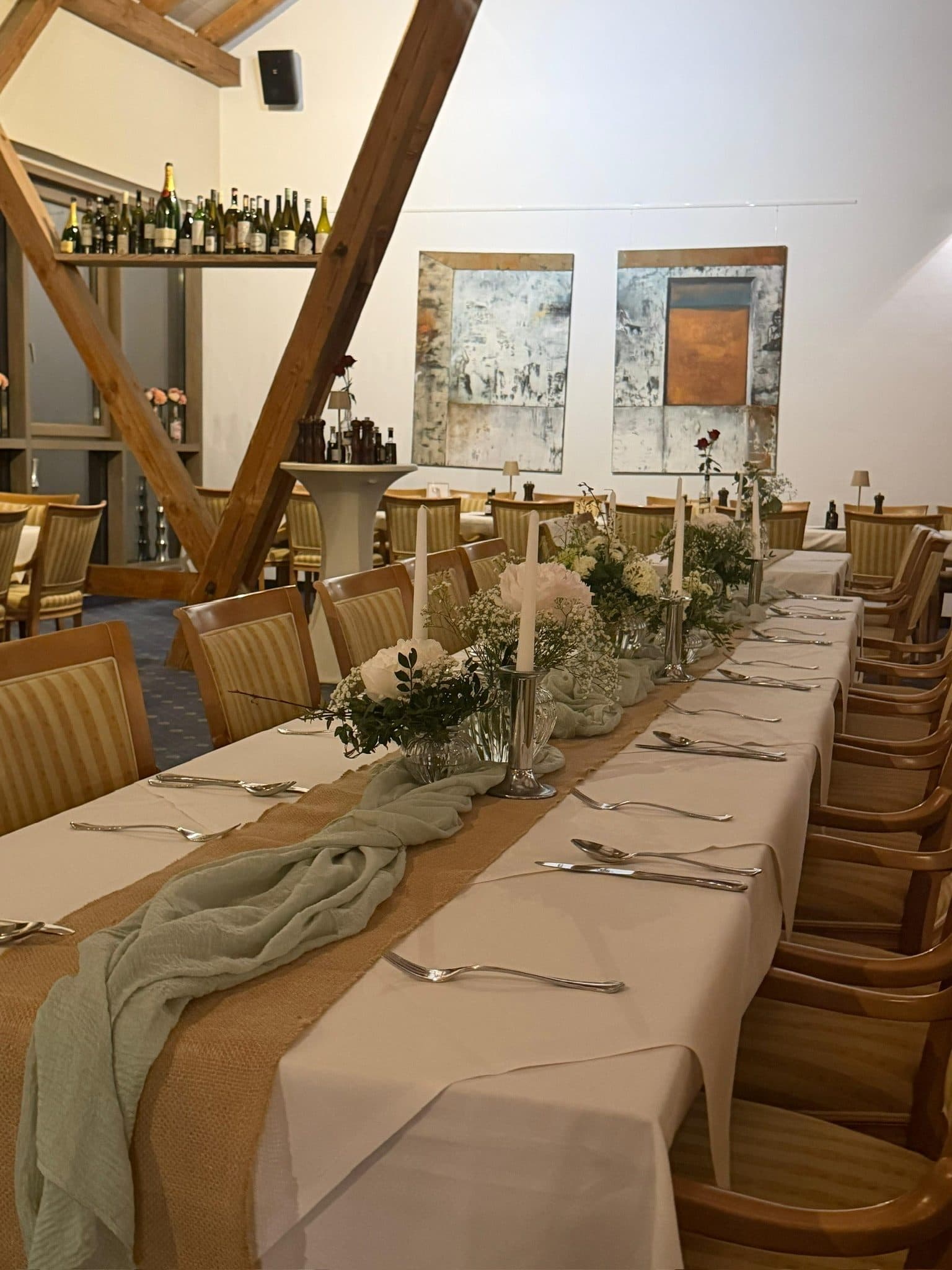 Lange Festtafel mit Blumengestecken und Tischläufer im Gastraum