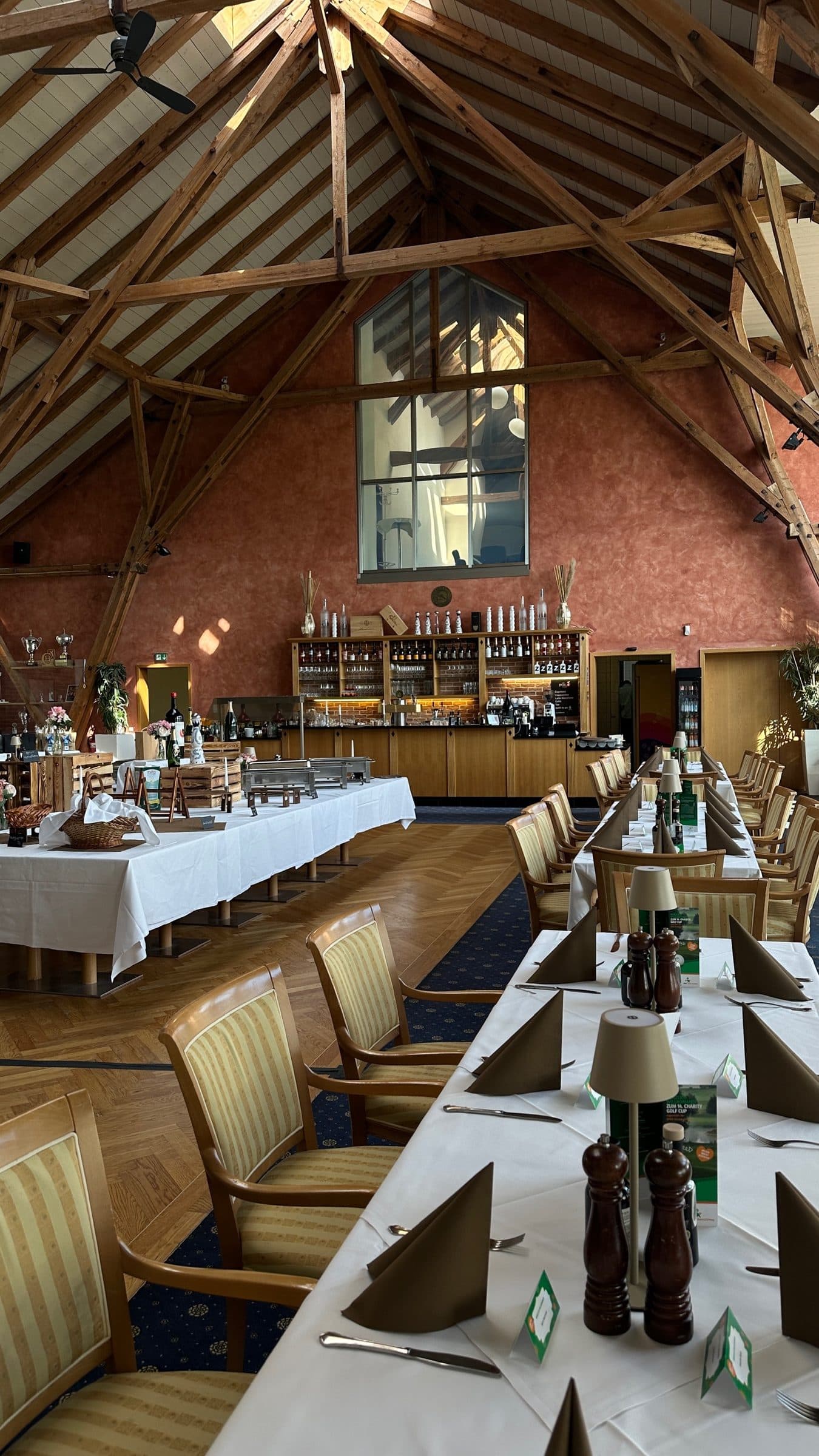 Tables laid beneath the timber roof, with the bar and the tall gable window behind